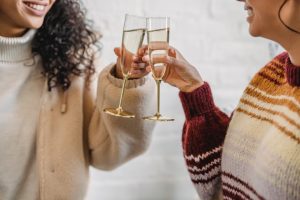 two women clinking champagne flutes together for cheers