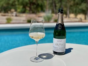 bottle of non-alcoholic Champagne with a wine glass by a pool